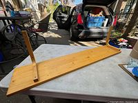 Wall shelf positioned on a table outdoors showing the top surface and two side brackets attached underneath for mounting.
