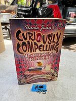 Front cover of Uncle John's Curiously Compelling Bathroom Reader book showing colorful design with toilet paper rolls and rubber duck.
