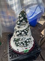 Full view of the Christmas tree decoration showing snowy village setting with light plug connected at the base.