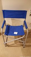 Blue foldable camp chair with fabric seat, backrest, padded armrests, and silver aluminum collapsible frame.