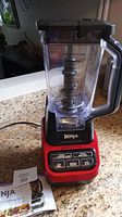Full view of the Ninja Professional Blender 1000 with red base, control panel, clear blender pitcher with handle and lid.