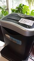 Side view of first black and silver paper shredder with price tag showing 150