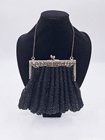 Front angled view of antique black glass bead purse with decorative silver tone metal frame and chain.