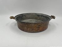 Side view of the antique copper pan showing the round shape and patina on the exterior.