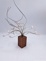 Full front view of the bone and wood sculpture showing wooden block base, wire stems and bone floral tips