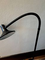 Close-up side view of the lamp's flexible neck and shade showing black metal construction.