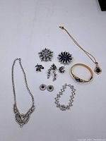 Full lot display showing all jewelry pieces: rhinestone necklace, brooches, earrings, gold-tone bracelet and necklace.