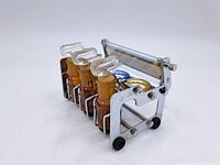 Photo showing side angle of the vintage German perfume testing kit with 3 amber glass bottles with glass stoppers and metal holder with small wheels.