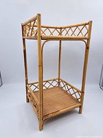 Front angle view of vintage wicker 2 tier shelf showing bamboo frame and woven base