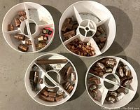 Four white segmented trays filled with various new copper plumbing fittings including elbows, tees, couplings, and sweat adaptors.