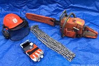 Full lot: chainsaw, extra chains, helmet, gloves on blue tarp