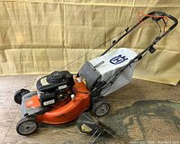 Full view of mower with grass catcher and discharge chute on wooden floor