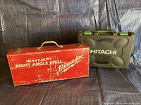 Two closed tool cases: red metal Milwaukee heavy-duty right angle drill case and black Hitachi plastic case.