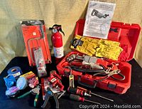 Wide view showing the Milwaukee right angle drill case open with drill, power cord, gloves, and surrounding hand tools including pliers, screwdrivers, coping saw, electrical tapes, and vice grip