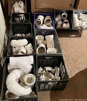 Multiple crates of white PVC fittings including elbows, couplings and hubs.