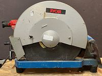 Front side view of Ryobi 355C 14-inch chop saw showing blade guard with Ryobi branding and blade in place.