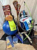 Wide view of sports equipment including lacrosse sticks, volleyball set, baseball glove, bow and arrows, exercise ball, cooler, and pumps