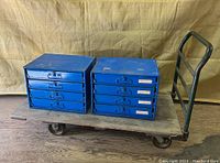 Two blue 4-drawer cabinets placed on a wooden-deck platform truck with metal handle and casters