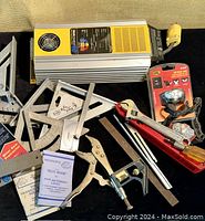 Photo showing Xantrex Truecharge 40+ battery charger with assorted metal T-squares, protractors, a wrench, grip tool, unopened dial caliper in packaging, and other steel tools.
