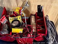 Photo showing open red Husky metal toolbox containing various electrical tools and accessories including wires, clamps, tape, multimeter.