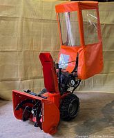 Front-side view of snowblower with cab and auger housing