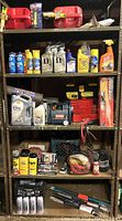 Shelf with various gas cans on top shelf, engine oils and treatments, and cleaning bottles. Ryobi 12V cordless inflator in center shelf with other automotive supplies and tools.