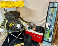 Camping set displayed including Mac Sports Captain's Chair with yellow canopy, Coleman cooler, Coleman stove, two Stinger bug zappers, and Quick Shade canopy in packaging.