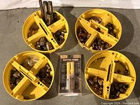 Four yellow plastic divided buckets filled with an assortment of copper plumbing fittings such as elbows, couplers, tube straps, and nipples. A copper pipe joint sealing tube is included in original packaging.