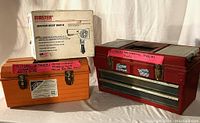 Photo showing original packaging of Master Appliance heat gun and two labeled toolboxes (orange and red) containing plumbing tools and supplies.