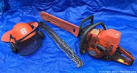 Full overview of chainsaw with guide bar cover, replacement chains and safety helmet