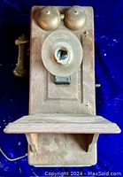 Front view of antique Kellogg oak magneto crank telephone box showing the mouthpiece housing and shelf below it, with aged wood surface and mounting details.