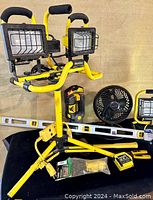 Workforce twin head 1000W halogen work light on yellow tripod stand with Stanley clamping flashlight, Honeywell fan, 25' tape measure, level, gloves and tools on black surface