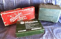 Three tool cases: red Milwaukee Super Sawzall, green Hitachi circular saw case, and green Metabo case with blades.