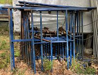 Stack of blue tubular scaffold frames with some accessories piled on top.