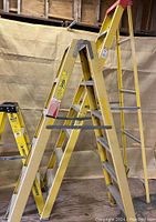 Side view showing all three fiberglass ladders of different heights with wear consistent with use.