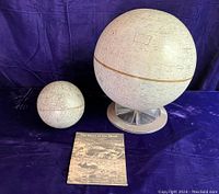 Photo of two vintage moon globes and the pamphlet together on dark fabric background.