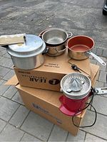 Full view of Breville electric juicer, cooking pots, and pressure cooker on cardboard boxes.