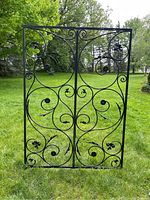 Front view of the double-panel black metal gate showing symmetrical scrollwork and leaf details.