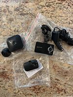 Photo showing three Blackview dash cams and accessories on a granite surface in clear plastic bags.