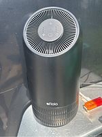 Front view of black cylindrical Floia Fillo air purifier showing the brand logo and ventilation grills.