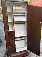 Full open view of the wooden jewelry armoire interior showing compartments, drawers, hooks, and padded ring rolls.