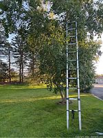 Full length photo of the aluminum folding ladder extended outdoors, showing multiple extension sections and black rubber feet.
