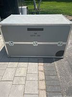 Front and top view of large gray rectangular storage case with metal edges and three butterfly locks.