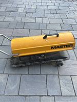 Side view of yellow cylindrical heater on black wheeled base