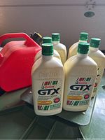 Photo showing 6 unopened 1 liter Castrol GTX motor oil bottles and one red 5 liter gas container.