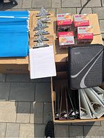 Photo of metal clipboards with attached lined notepads, boxes of OLO safety cutters, black binders, and white file folders organized in boxes.