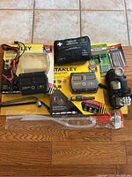 Full lot overview showing Stanley battery boosters, Mercedes Benz first aid kit, booster cable, tire wrench, Husky tire inflator, Slime/Welson tire plug kit, and siphon pump.