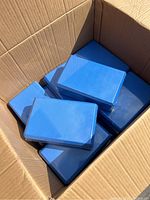 Box filled with multiple new blue yoga blocks wrapped in plastic.
