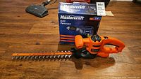 Mastercraft electric drill box with Black & Decker hedge trimmer beside it on wooden floor
