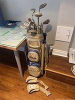 Beige and blue Fila branded golf bag containing complete set of women's golf clubs including irons 4-9, sand and pitching wedges, driver, 3 wood, 5 wood, and mallet putter